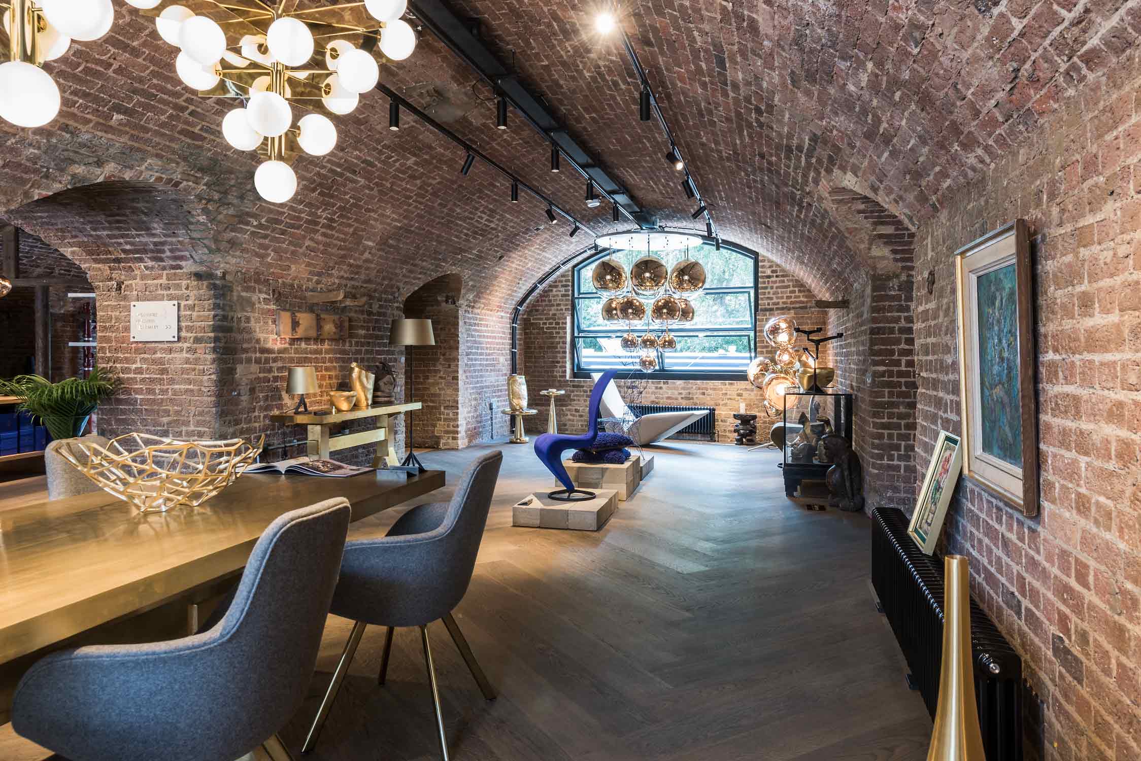 Innenansicht des Shops von Tom Dixon. Backsteingewölbe, Holzboden und coole Möbel und Leuchten.