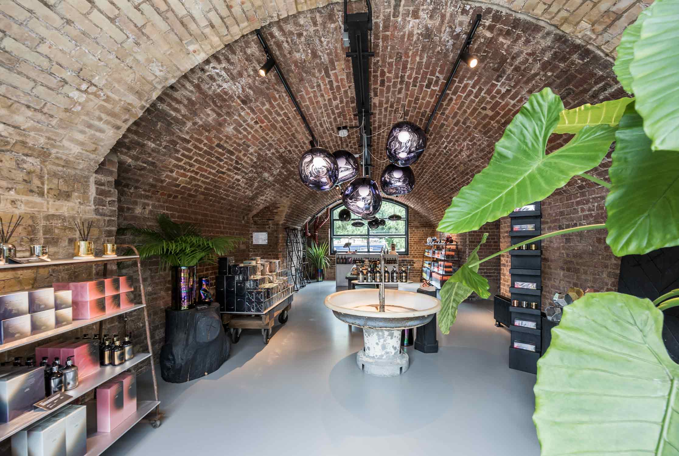 Innenansicht des Shops von Tom Dixon. Backsteingewölbe, Holzboden und coole Möbel und Leuchten.