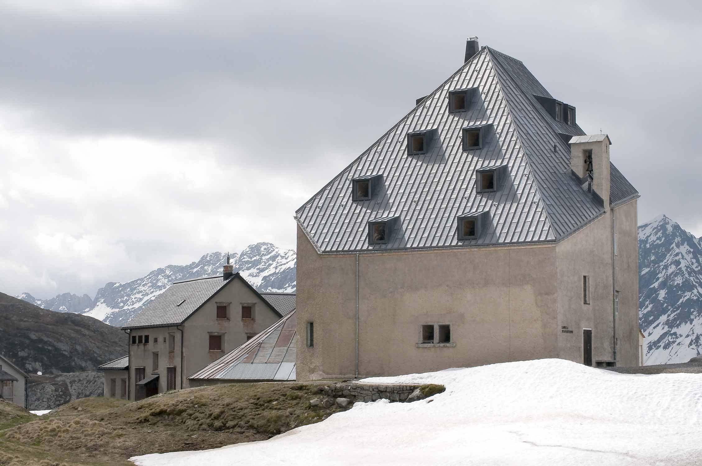 Aussenansicht des Gebäudes am See liegend, mit Schnee und wolkigem Himmel.