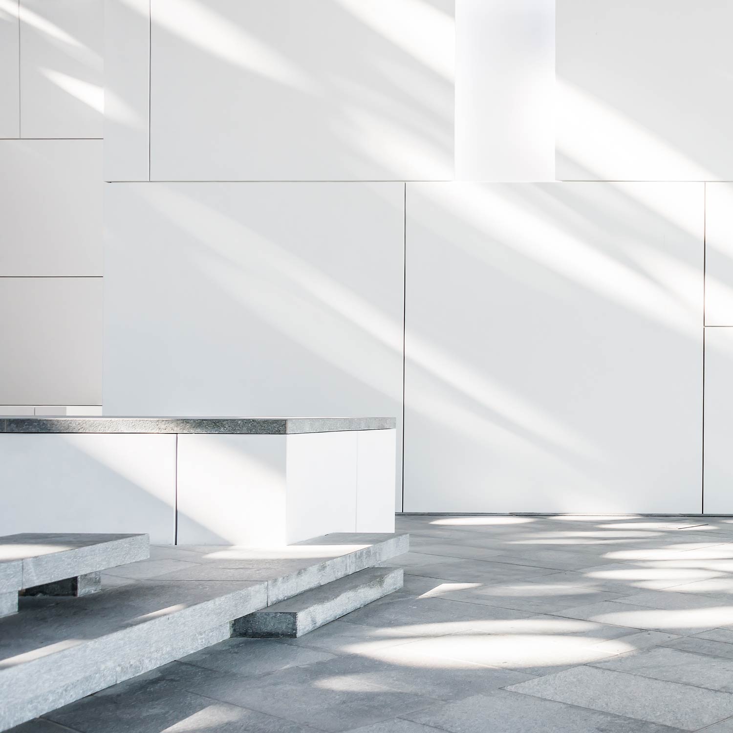 Innenhof im Kunstmuseum Louvre von Jean Nouvel in Abu-Dhabi. Weisse Baukörper mit riesigem Kuppeldach, das Lichtstrahlen, wie einen Lichtregen durchlässt.