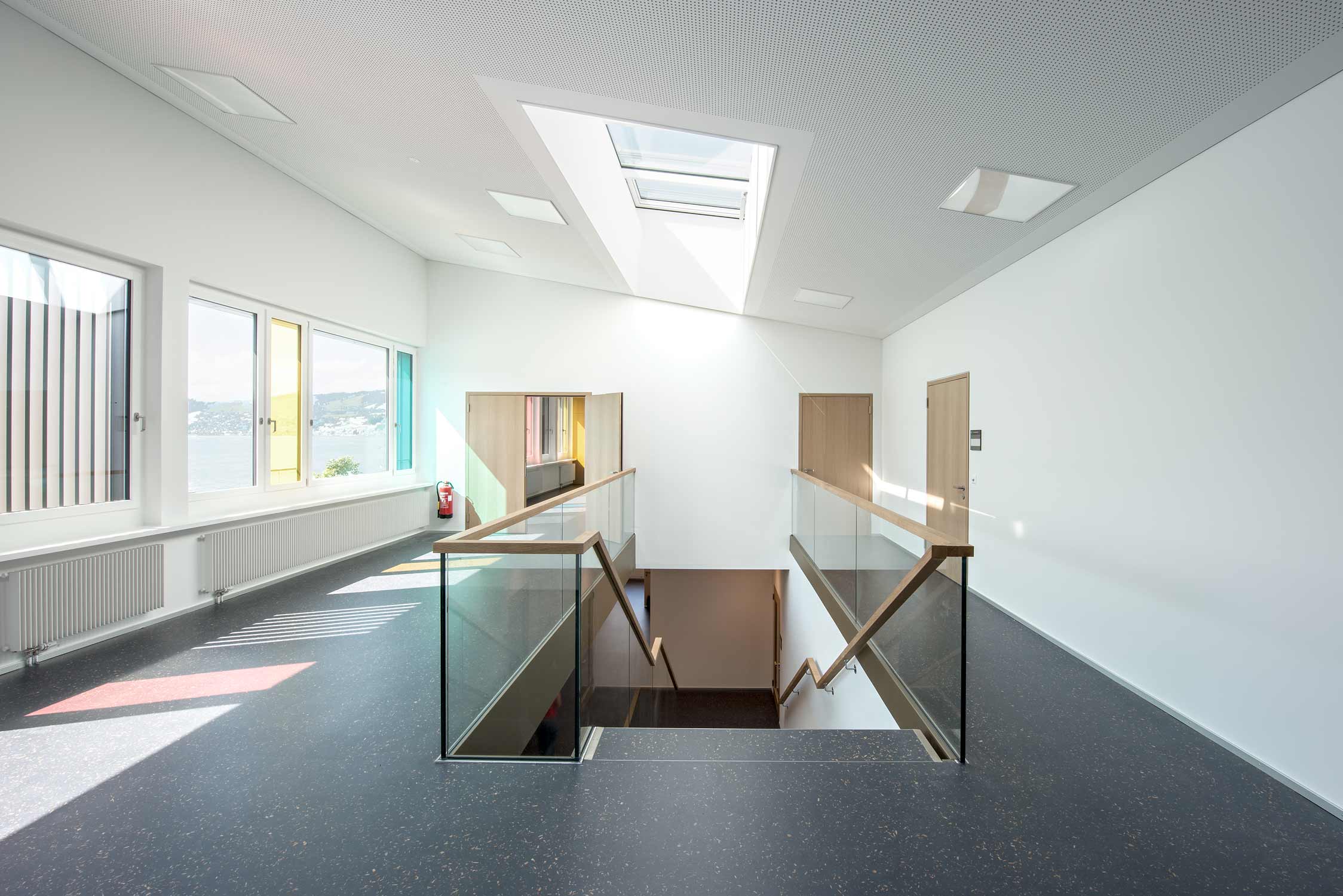 Treppenbereich und Flur des Schulhauses Morgarten sind lichtdurchflutet und durch farbige Fensterscheiben ergibt sich ein schönes Farbenspiel.